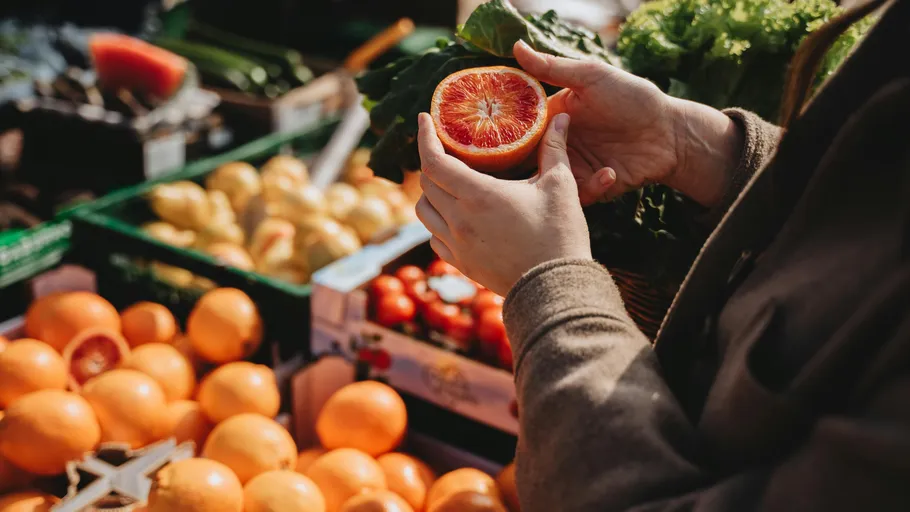 Person hält eine aufgeschnittene Orange am Markt.