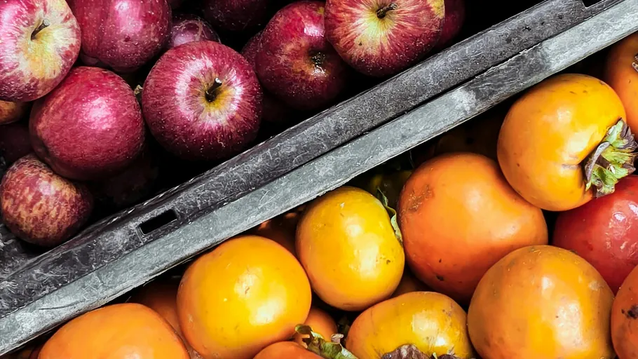 Apples and persimmons in wooden crates.