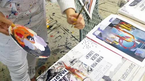 Person painting on a table with colorful palette.