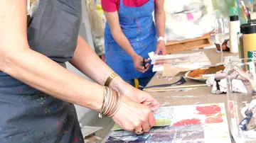 Zwei Personen fertigen Kunst auf einem Tisch an.