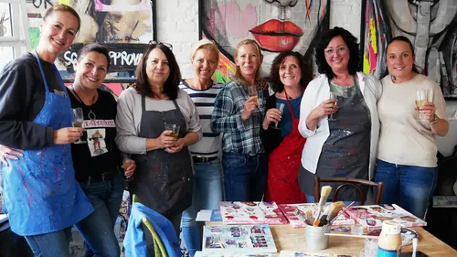 Group of people smiling with drinks, art studio.