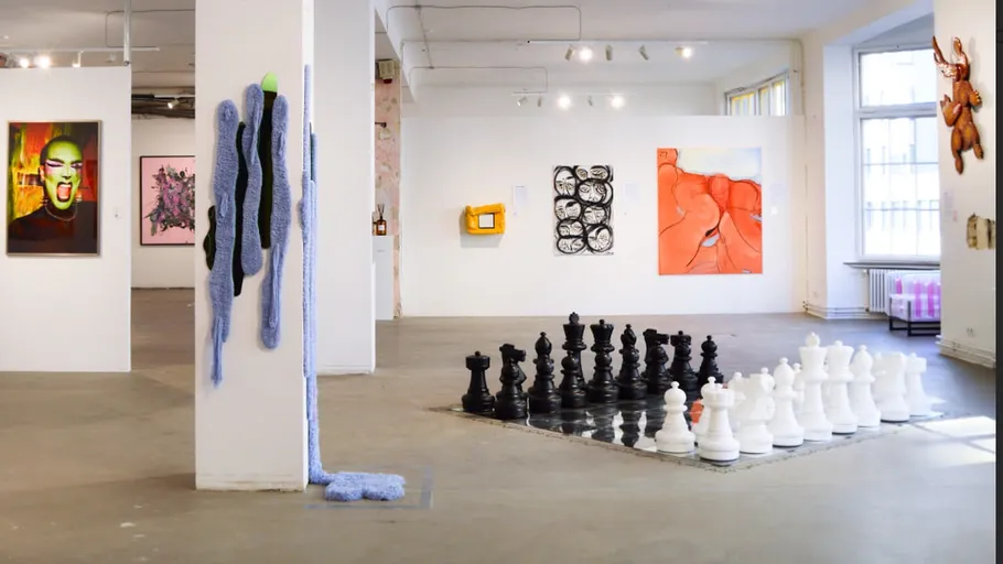 Kunstgalerie mit Gemälden und großem Schachset.