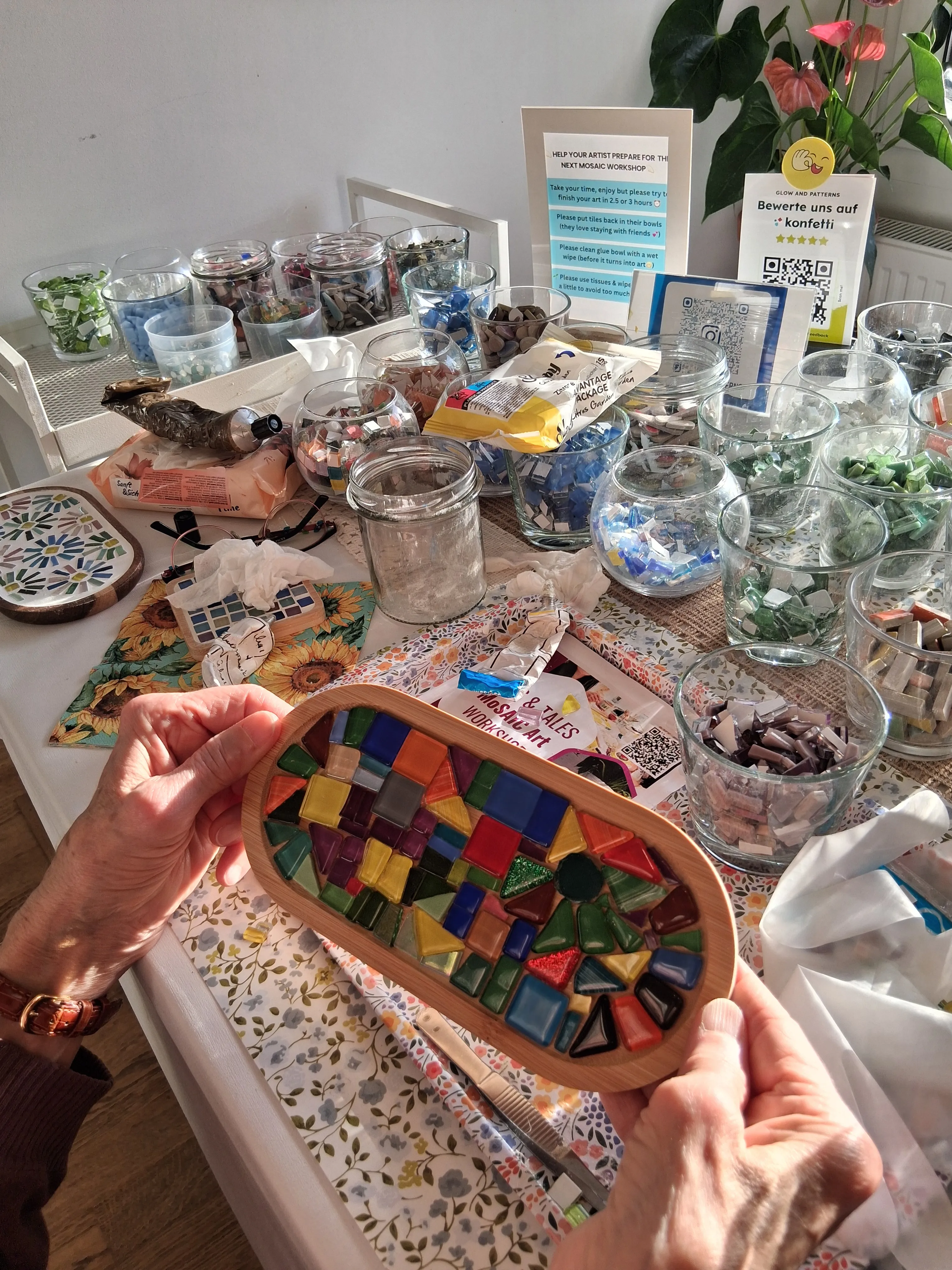 Hände halten buntes Mosaik auf Werkbank.