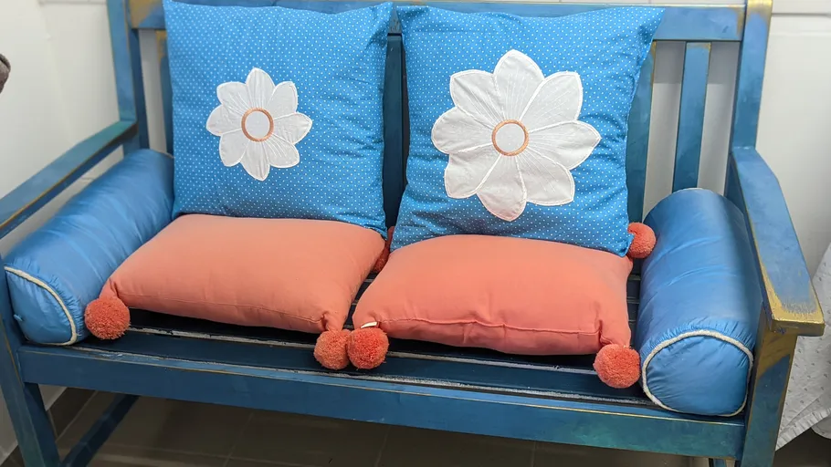 Bunte Kissen auf einer blauen Holzbank.