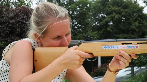 Woman aiming wooden laser rifle outdoors.