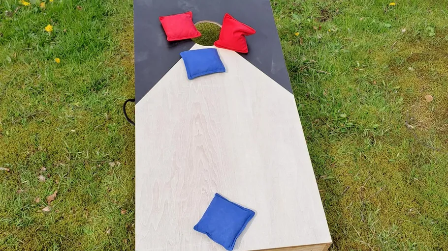 Cornhole board with colored bean bags outdoors.