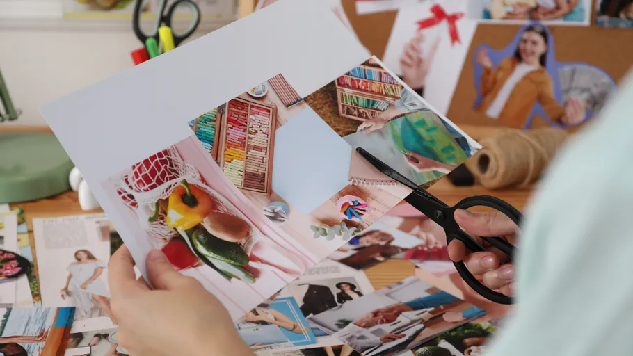 Person cutting collage on creative workspace.