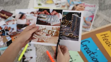 Hands cutting collage images on a table.