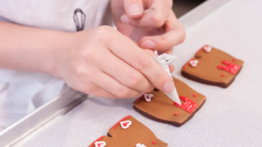 Person decorating cookies with red icing.