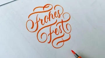 Orange calligraphy reads 'Frohes Fest' on paper.