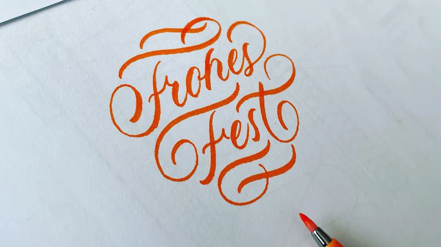 Orange Kalligrafie 'Frohes Fest' auf Papier.