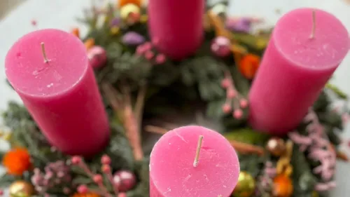 Pinke Kerzen auf einem festlichen Adventskranz.