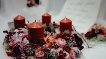 Rote Kerzen umgeben von Zierblumen.