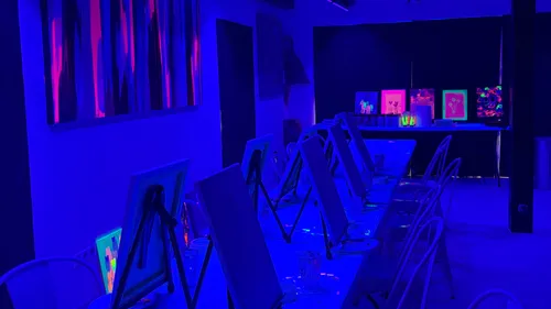 Canvases on easels under blue lighting.