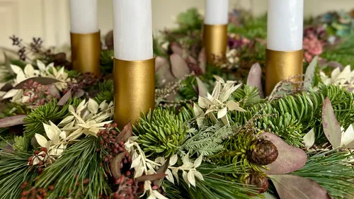 Candles in wreath with green foliage.
