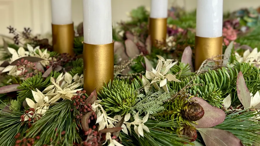 Candles in wreath with green foliage.
