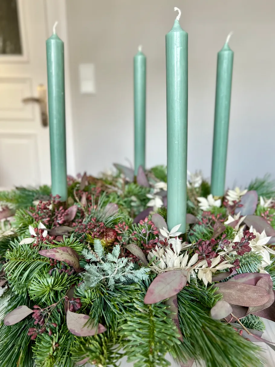 Grüne Kerzen in einem festlichen Kranz.