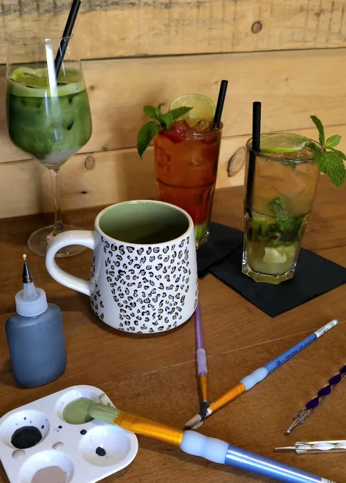 Getränke und bemalte Tasse auf Holztisch.