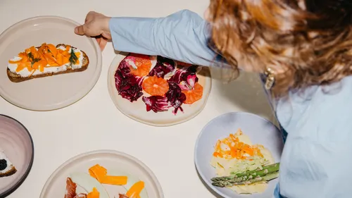 Person arrangiert bunte Essteller mit Essen.
