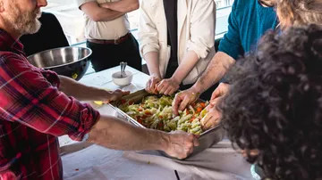 Menschen bereiten gemeinsam Essen in Küche zu.