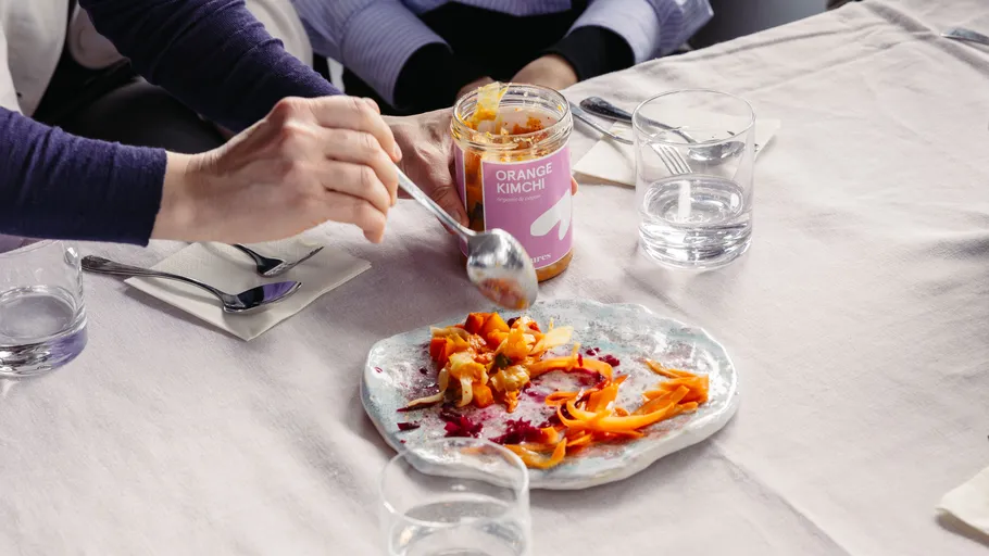 Person serving kimchi at a dining table.