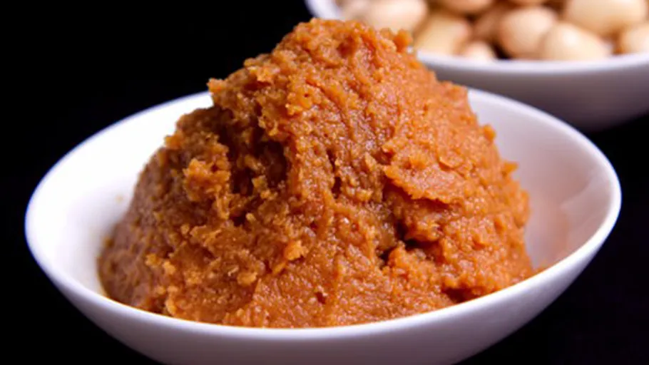 Brown paste in white bowl, black background.