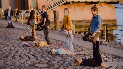 People practicing yoga on a riverside walkway.