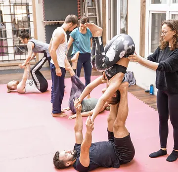 Group practicing acro yoga indoors on mats.