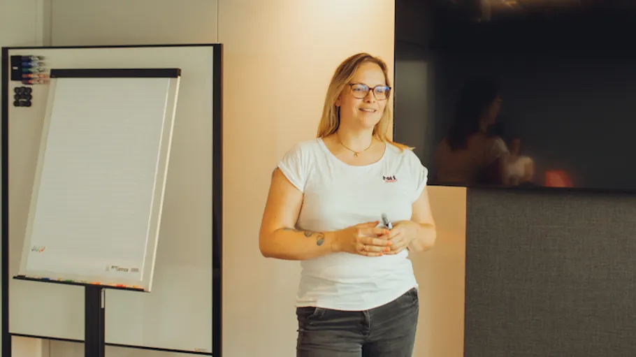 Woman holding marker near whiteboard, smiling.