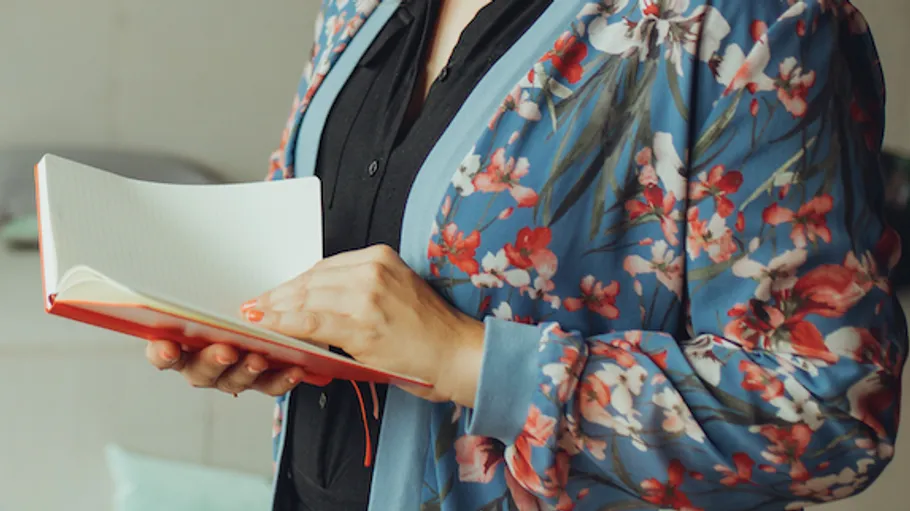 Person in floral jacket holding a notebook.