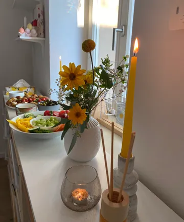 Gelbe Blumen und Kerzen auf einem Esstisch.