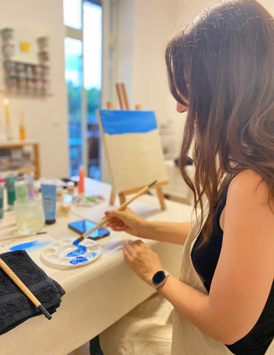 Woman painting at a table in a studio.