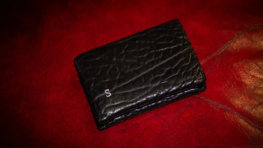 Black wallet on red textured surface.