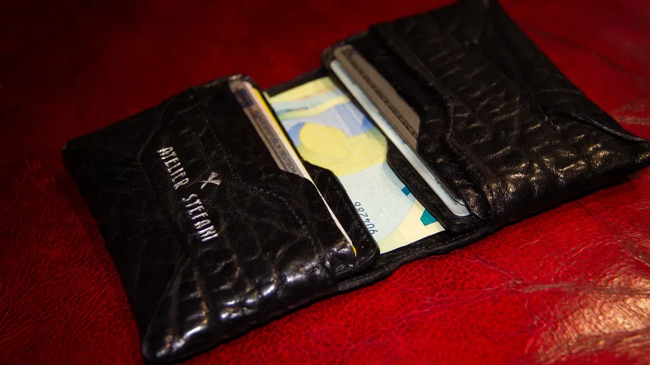 Black wallet with cards on red surface.