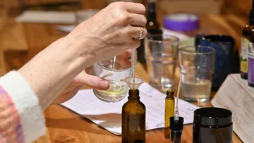 Person pouring liquid into bottle with dropper.