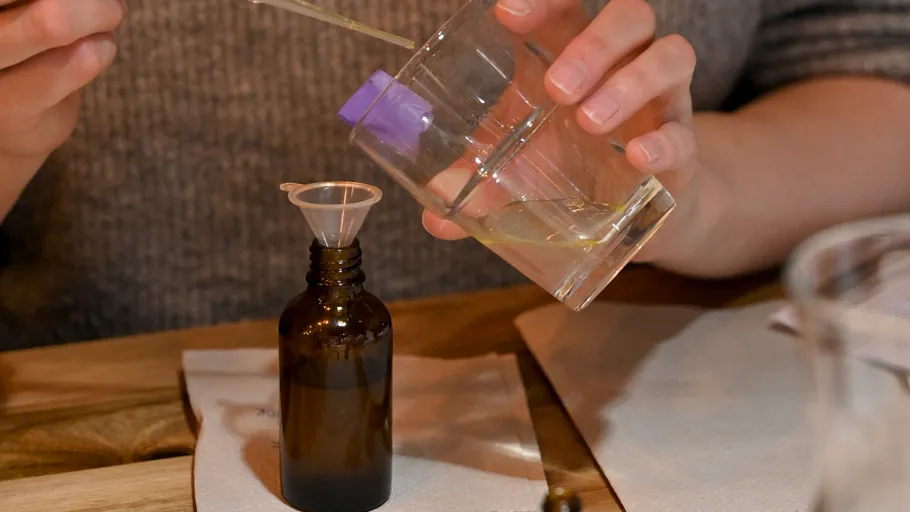 Person pouring liquid into small bottle.