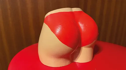 Red swimsuit sculpture on red surface.