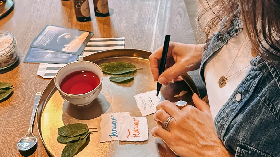 Person writing at table with tea.