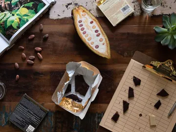 Cocoa beans are on the table next to opened chocolate.