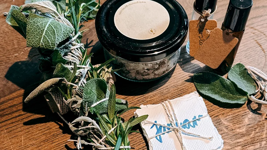 Herbs, jar, bottles, and card on wooden table.