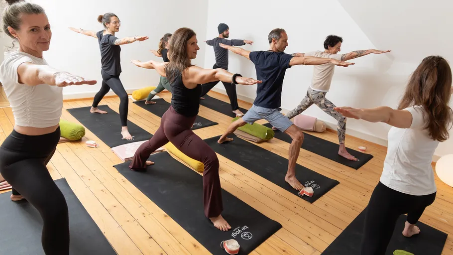 Menschen praktizieren Yoga in einem Studio.