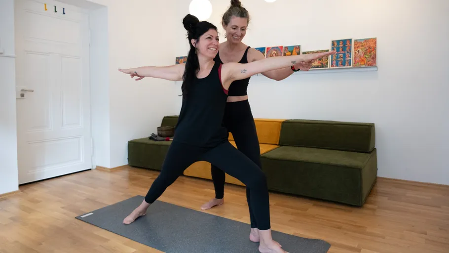 Zwei Frauen praktizieren Yoga im Wohnzimmer.