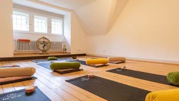 Yogamatten und Kissen in geräumigem Raum.