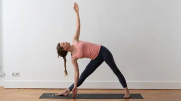 Frau macht Yoga-Pose auf Matte drinnen.