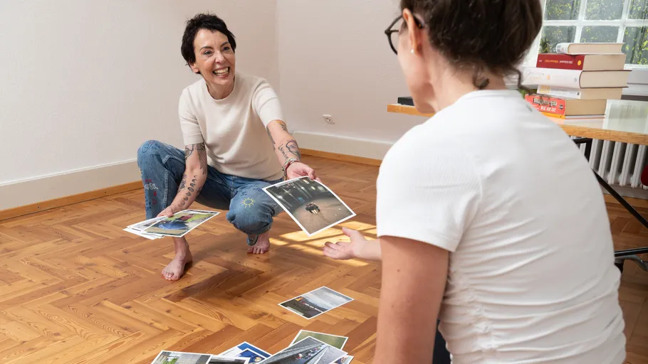Two people interact with photos on floor.