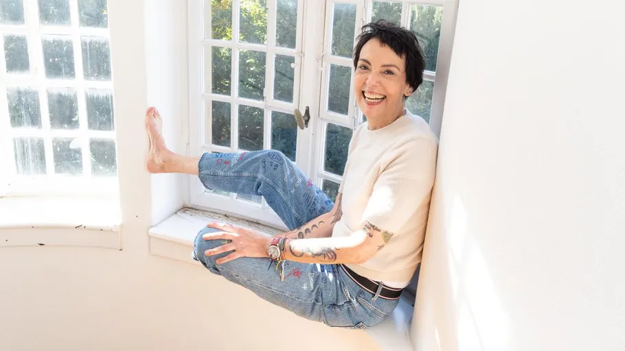 Smiling person sitting on sunny windowsill.