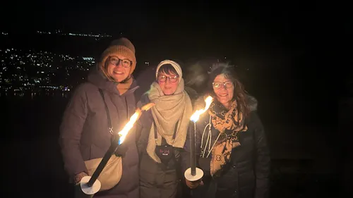 Three women holding torches at night.