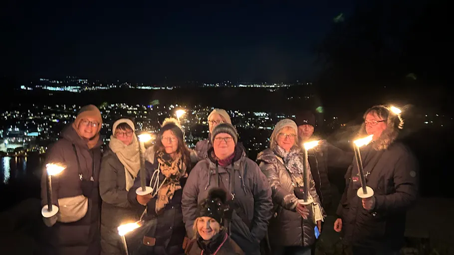Group holding torches overlooking cityscape at night.