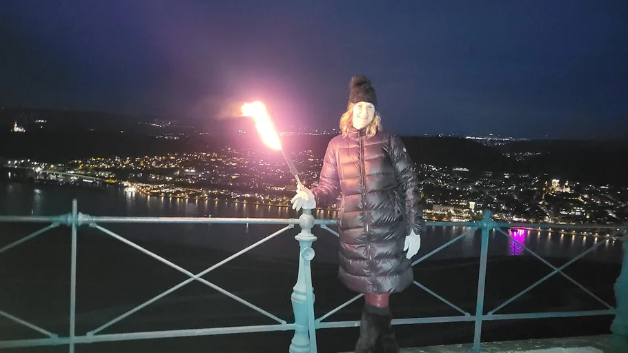 Person holds torch on nighttime balcony.