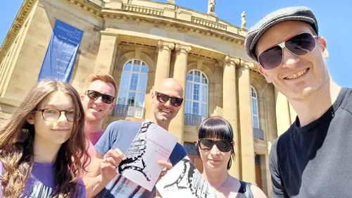 Gruppe von Menschen lächelt vor einem Gebäude.